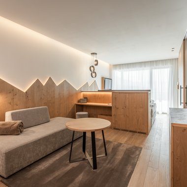Urlaub mit Hund: Südtirol entdecken Modern eingerichtetes Hotelzimmer mit Sitzbereich und Holzmöbeln