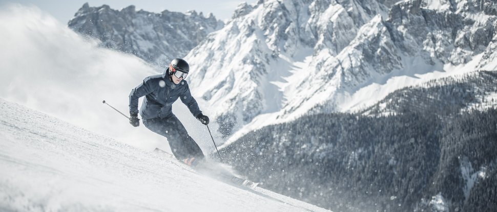 Our 5-star hotel in Italy between heaven and earth Skier skiing on snowy slope with large mountains in the background