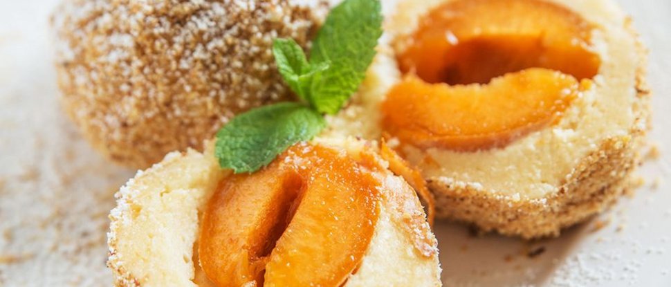 Unser Hotel in Olang zwischen Himmel und Erde Marillenknödel mit Zucker und Minzblatt auf weißem Teller