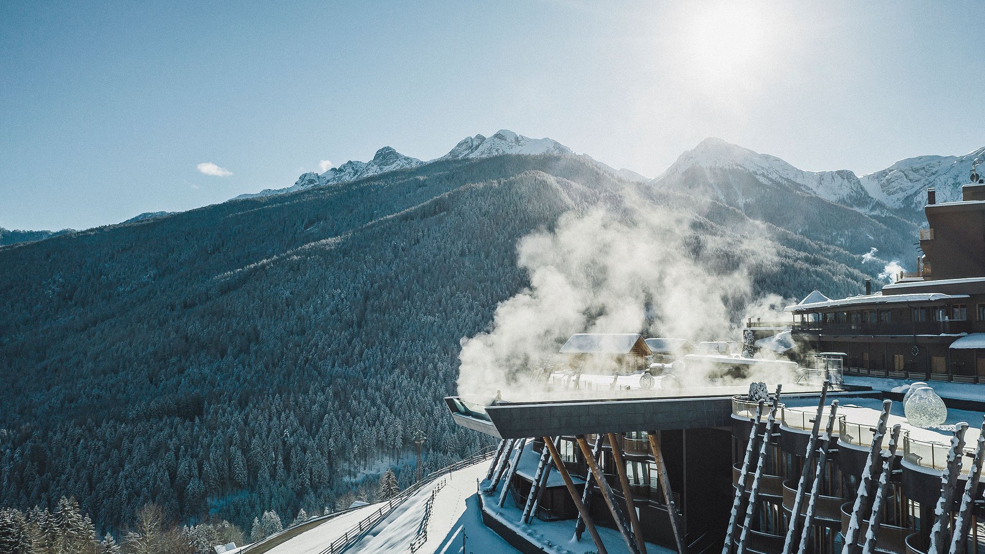 Unser Hotel in Olang zwischen Himmel und Erde Schnee bedecktes Berghotel mit rauchendem Kamin und Sonnenschein