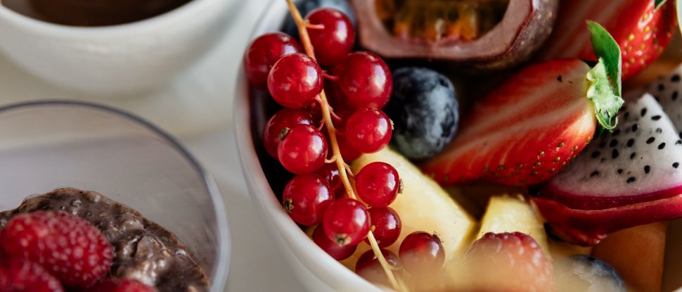 Unser Hotel in Olang zwischen Himmel und Erde Schüssel mit frischem Obst, Chia-Pudding und Schokolade auf weißem Tisch