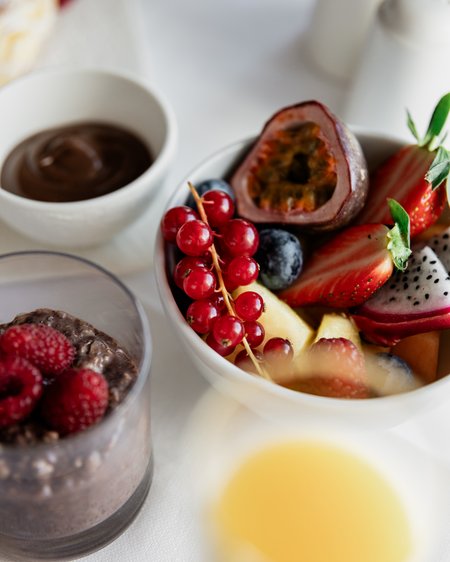 Unser Hotel in Olang zwischen Himmel und Erde Schüssel mit frischem Obst, Chia-Pudding und Schokolade auf weißem Tisch