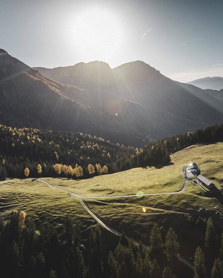 Unser Hotel in Olang zwischen Himmel und Erde Sonnenlicht über einer grünen Alm in den Bergen mit einem kleinen Haus