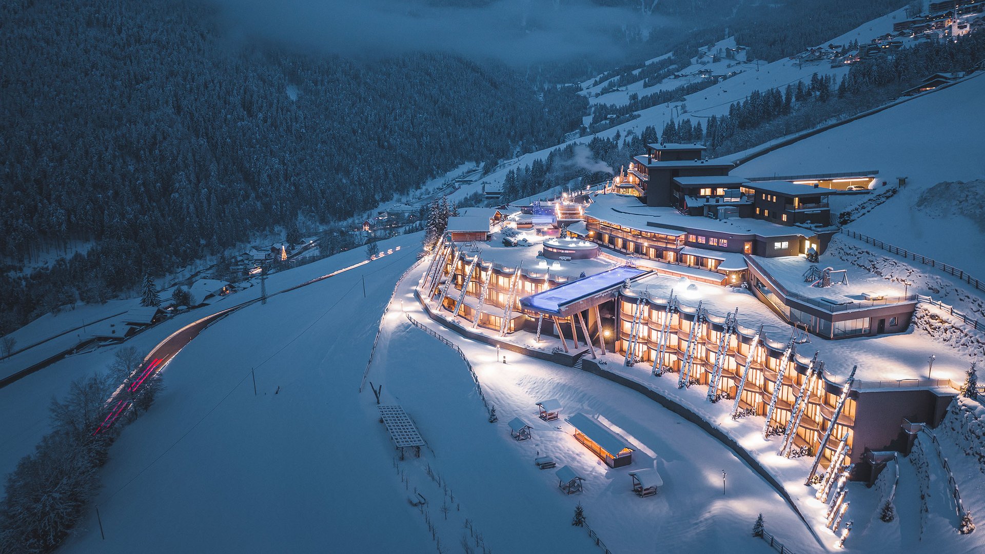 From Olang to the Lake Braies Illuminated modern mountain hotel in snowy valley at night