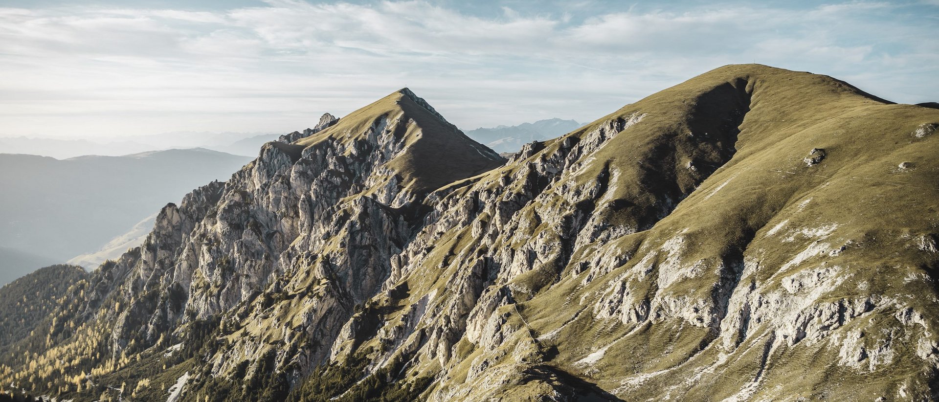 Unser Hotel in Olang zwischen Himmel und Erde Berggipfel mit felsigen Klippen und grasbewachsenen Hängen unter blauem Himmel
