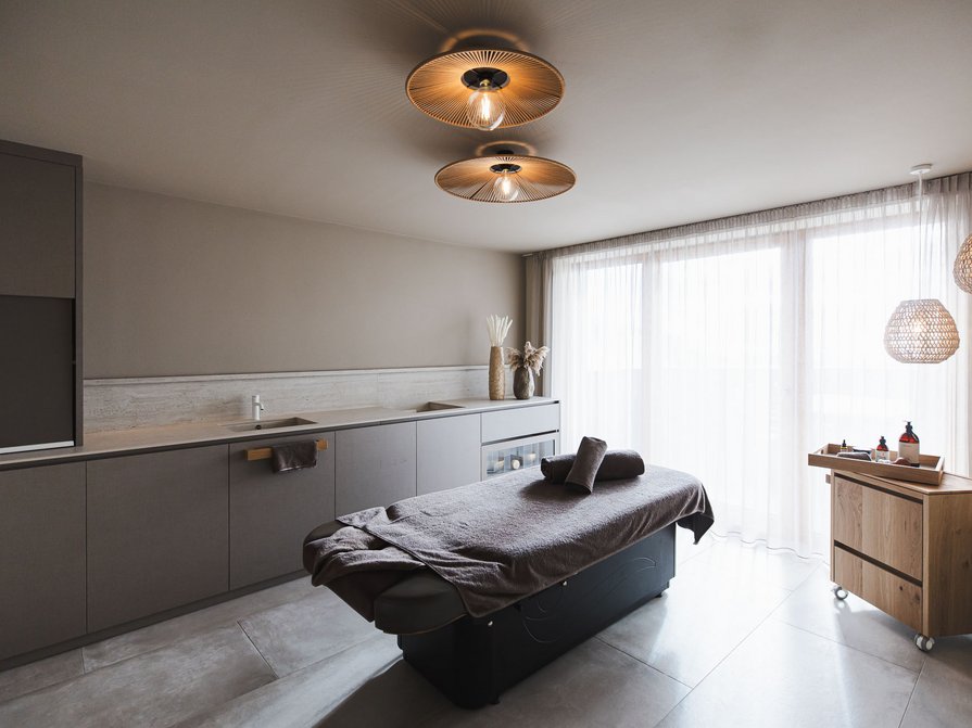 Unser Hotel in Olang zwischen Himmel und Erde Moderner Massageraum mit Liege und gedämpfter Beleuchtung